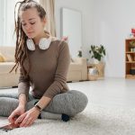 Pretty girl with headphones going to listen to yoga audio in smartphone